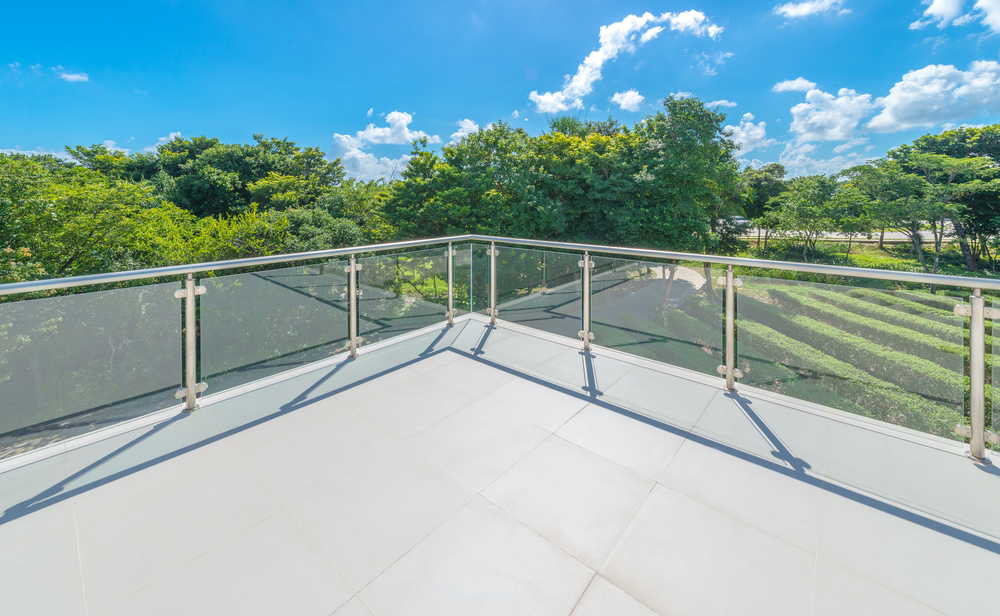 Terraza de casa en zona residencial, con barandal de vidrio templado y pasamanos inoxidable