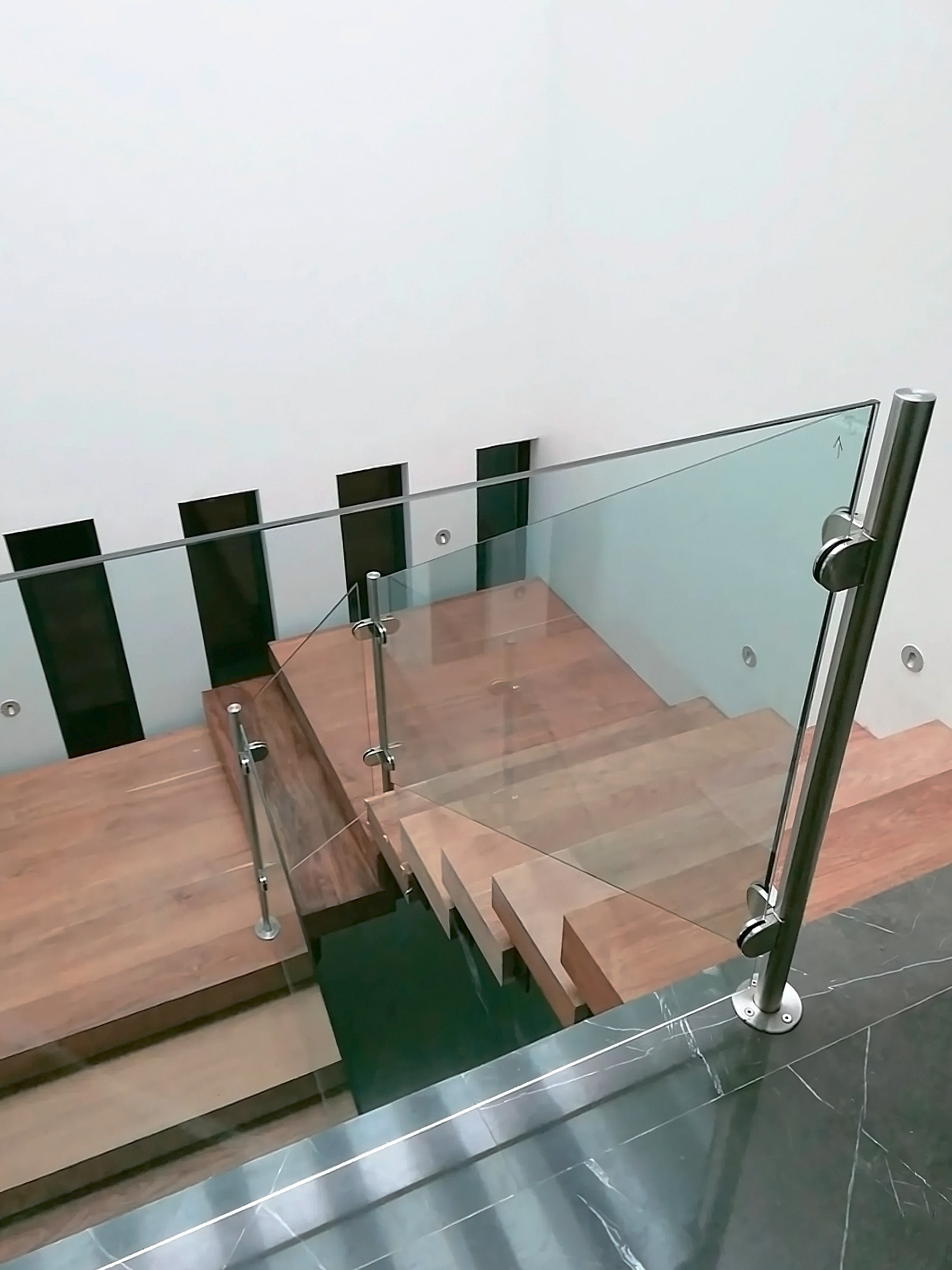 Barandal de vidrio templado con postes inoxidables en escalera flotante de madera