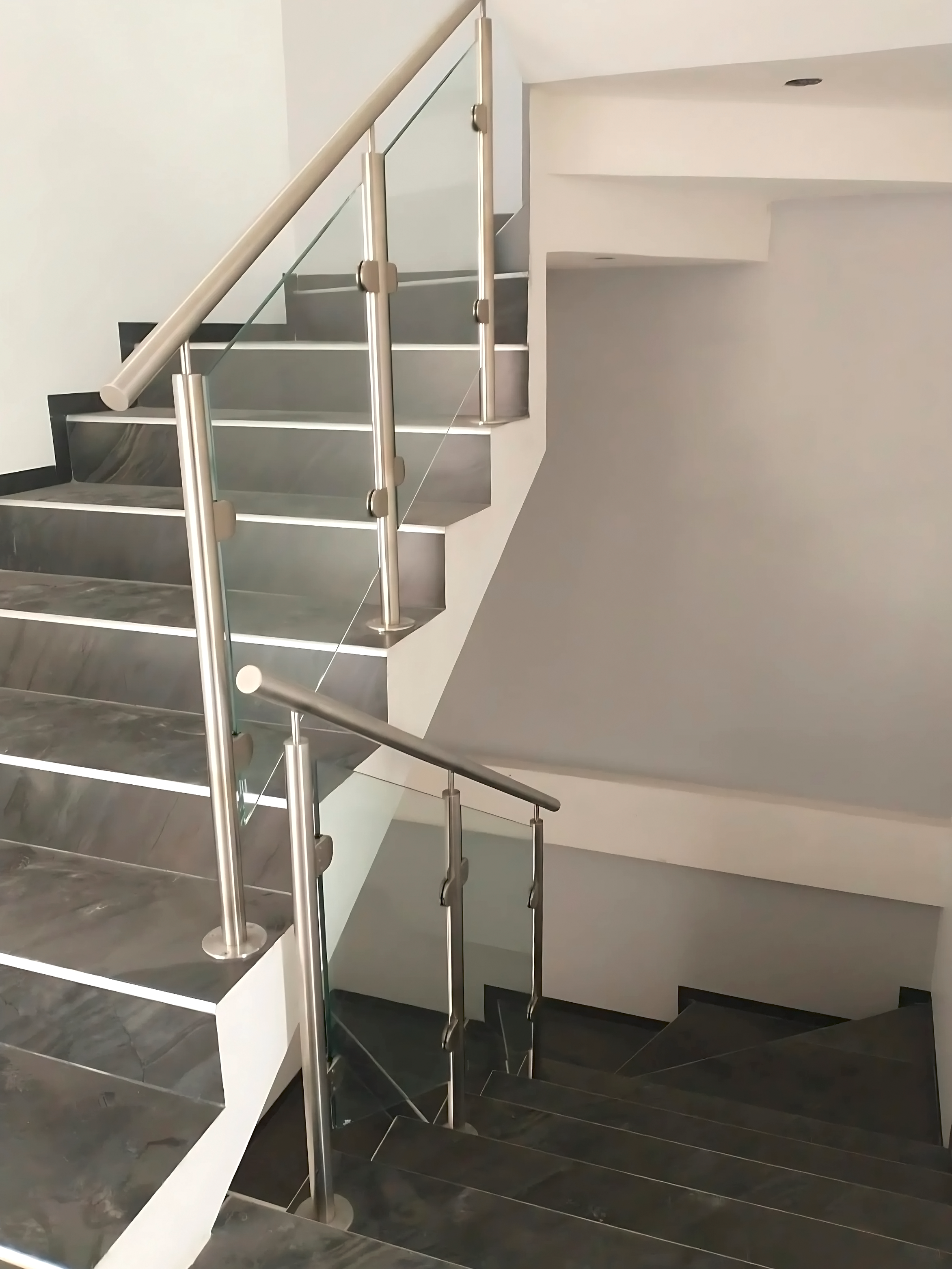 Barandal de vidrio templado con postes inoxidable en escalera  interior con acabado mármol