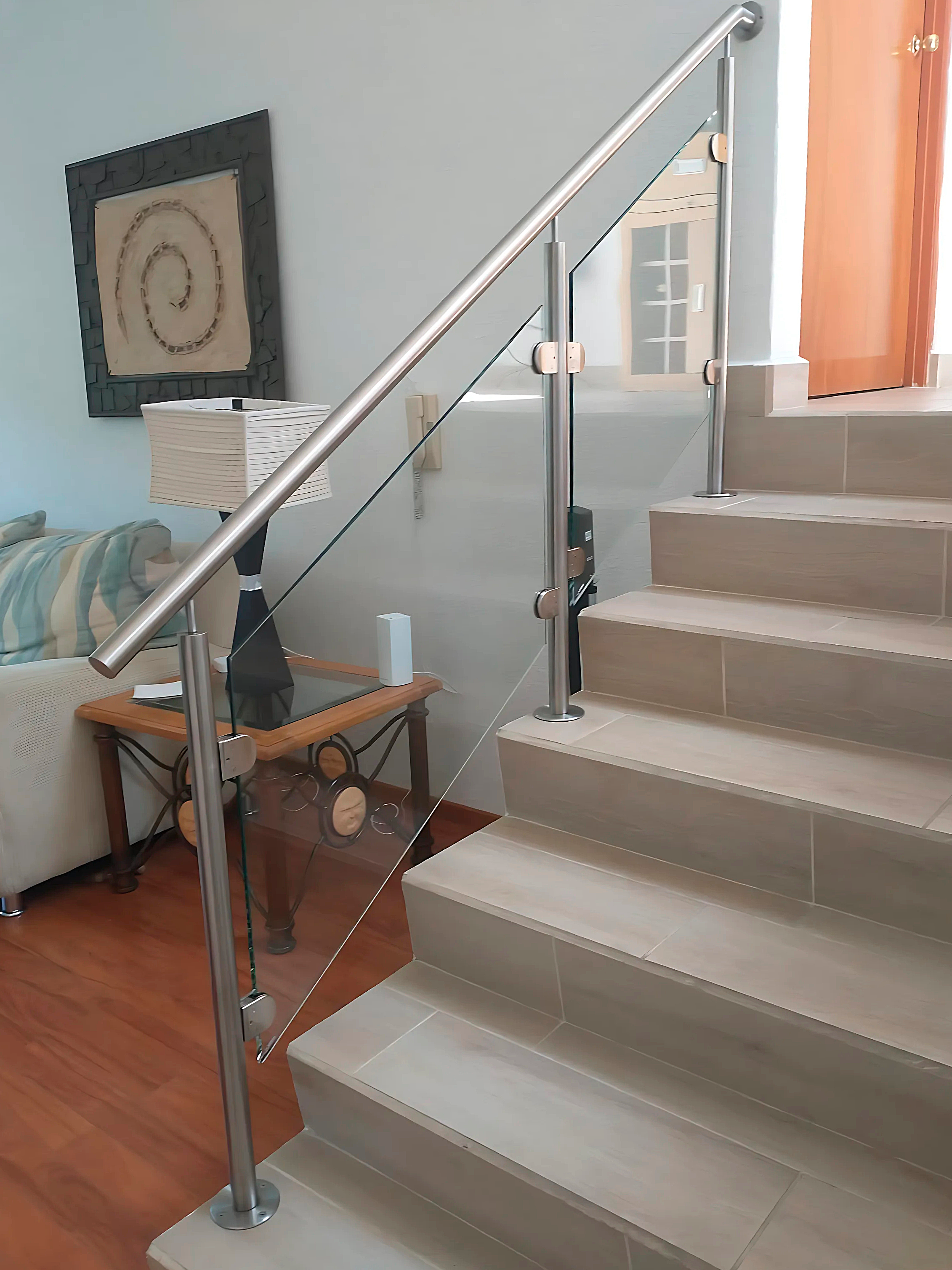 Barandal de vidrio templado y postes inox en escalera que bajan a sala en desnivel