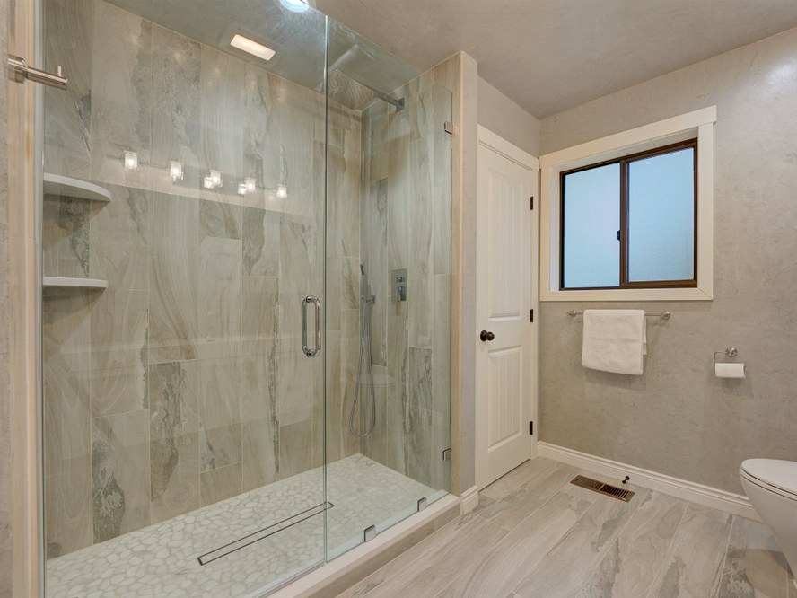 Cancel corredizo de vidrio templado en regadera de baño moderno con perfiles de aluminio pulido