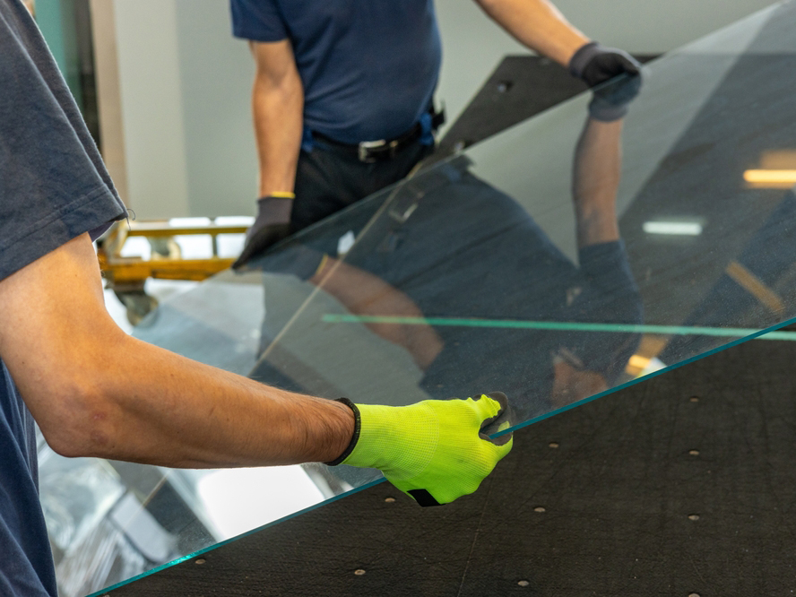 Instalación de barandal de cristal templado, operando en taller con guantes de seguridad