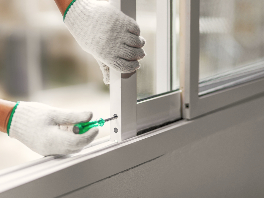 Técnico instalando marco de ventana corrediza de aluminio blanco, asegurando el perfil