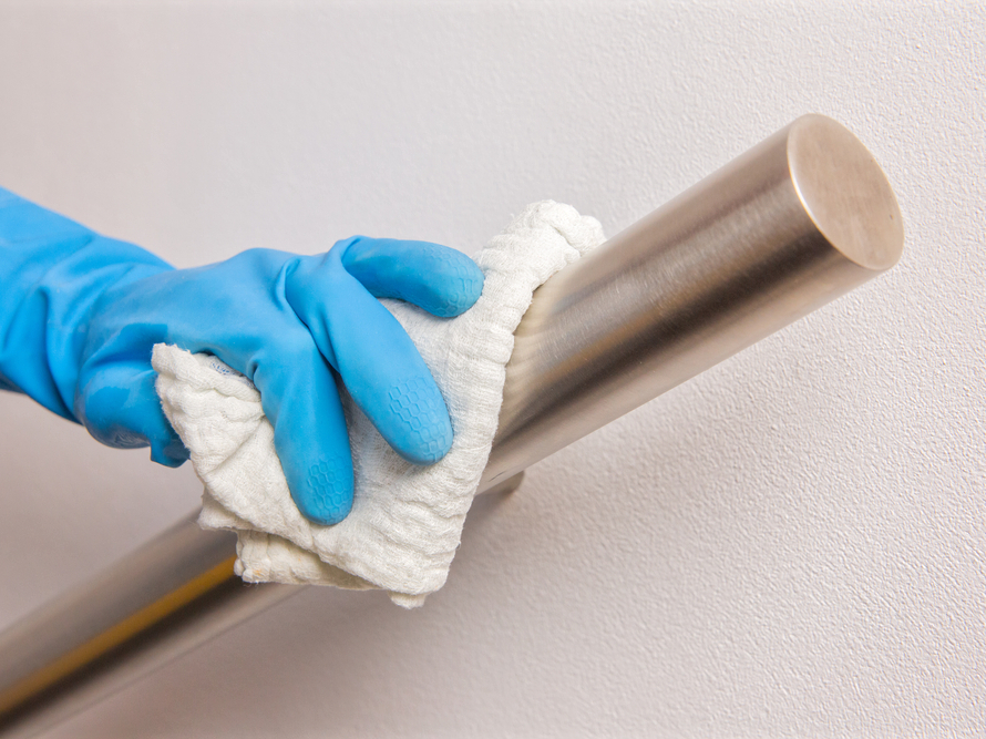 Guante azul limpia pasamanos satinado de acero inoxidable con paño, demostrando mantenimiento sencillo