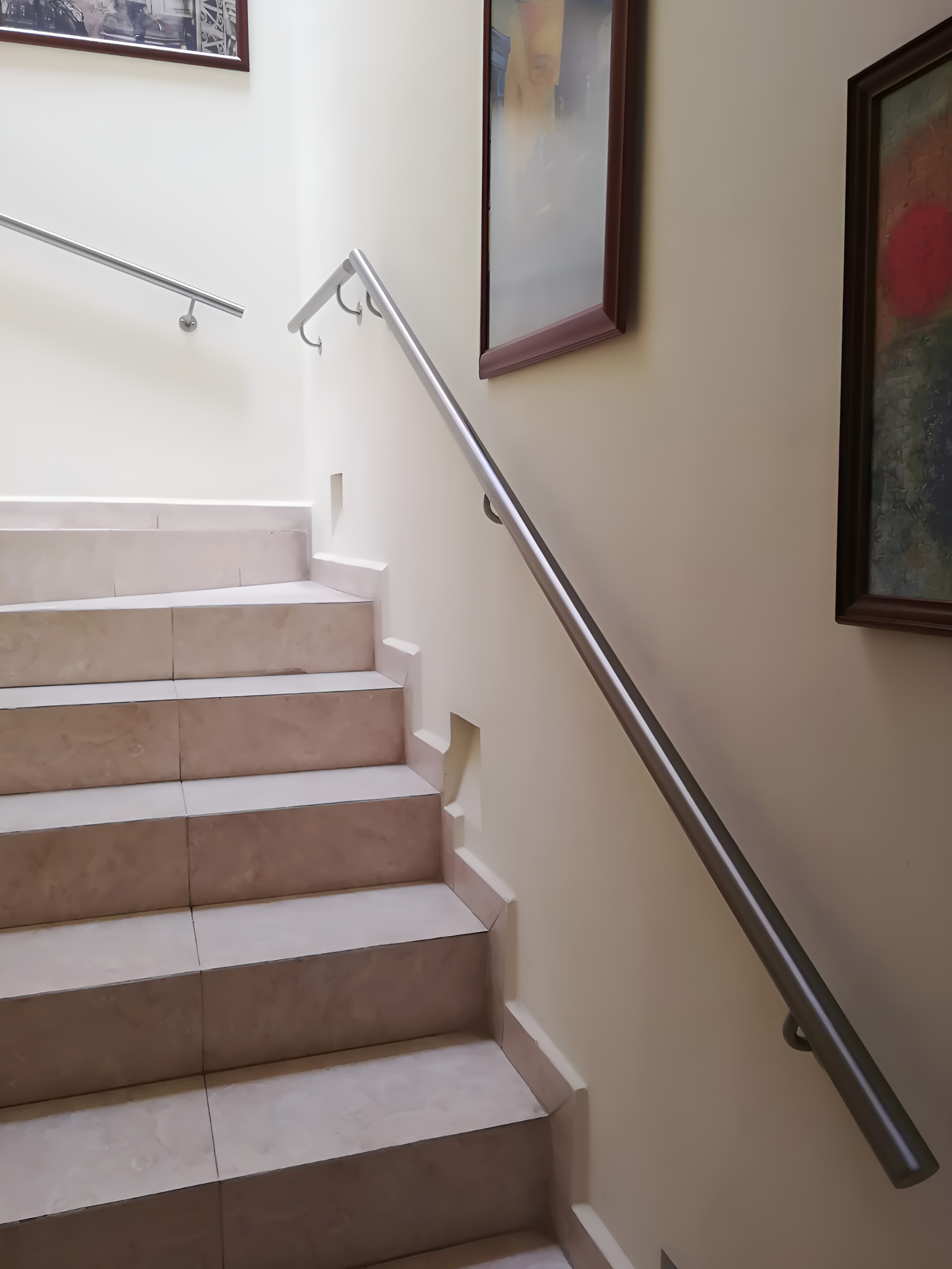 Pasamanos de acero inoxidable satinado fijado a muro en escalera interior de casa
