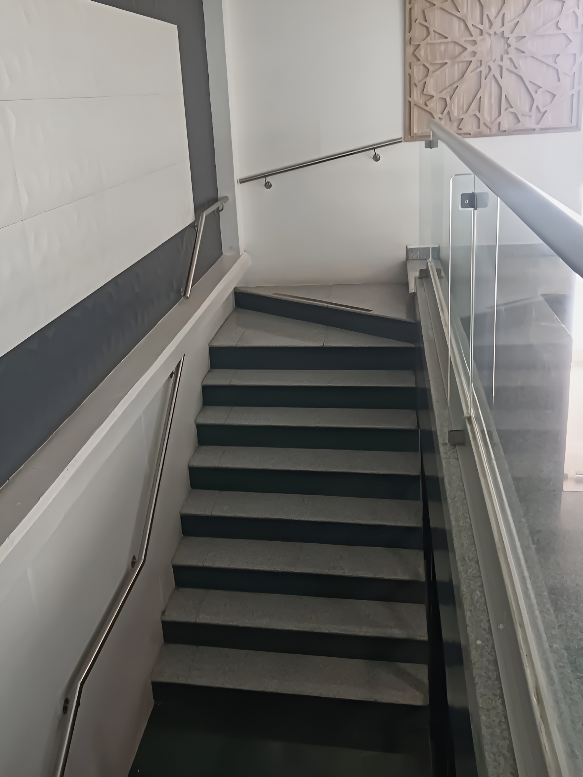 Pasamanos satinado doble nivel integrado a barandal de vidrio en escalera interior