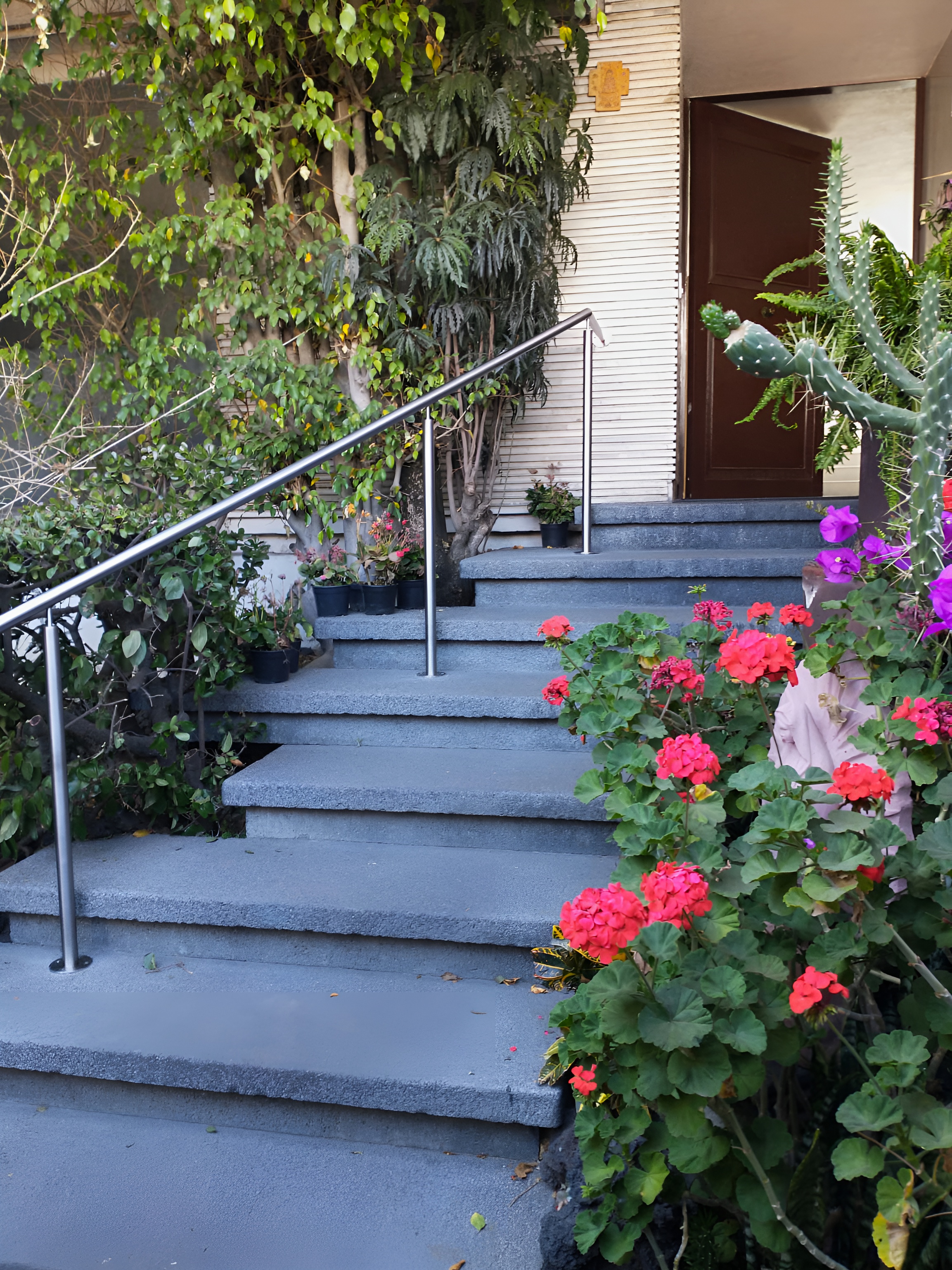 Pasamanos de acero inoxidable satinado instalado en escalera exterior rodeada de plantas