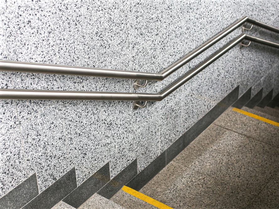 Doble pasamanos inoxidable paralelo en escalera de estacionamiento en plaza comercial
