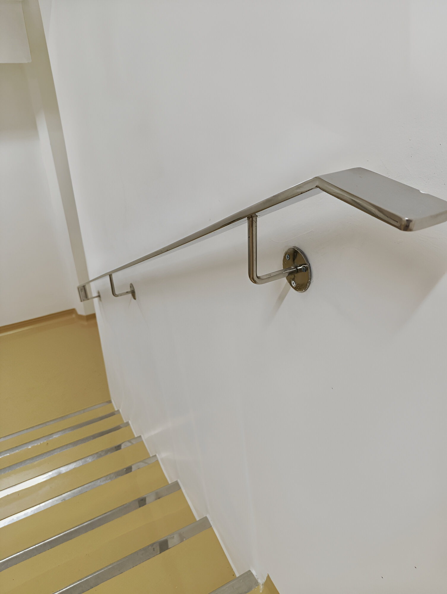 Pasamanos de acero inoxidable instalado en escalera de servicio, estilo industrial y funcional