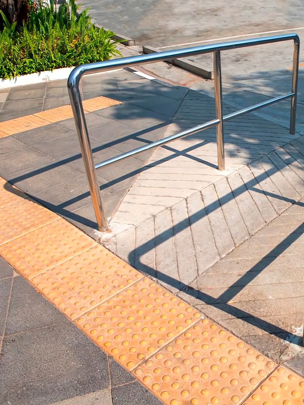 Pasamanos inoxidable con barandal guía en rampa accesible exterior, zona urbana