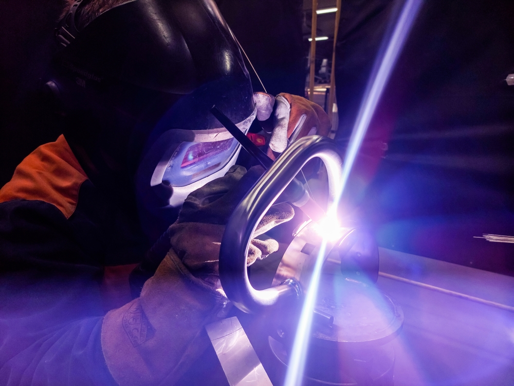 Soldador aplicando TIG en poste de barandal inoxidable durante fabricación en taller